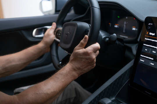 male hand on Driver's column, Behind steering wheel Polestar 2 electric car, modern passenger car, showcasing interior features such Control wheel, gear shift, front windshield and dashboard
