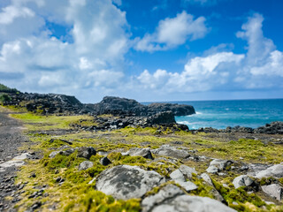 Coastal Majesty: Rocky Cliffs Beneath a Cloud-Adorned Blue Sky