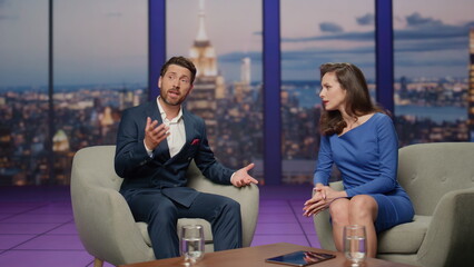 Two presenter talking tv show sitting armchairs studio. Bearded man telling news