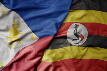big waving national colorful flag of uganda and national flag of philippines.