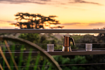 Kaffeekann und Tassen auf einer Terrasse im Sonnenaufgang