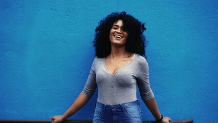 One hapyp young black Brazilian woman authentic real life laugh and smile standing in outdoor blue...