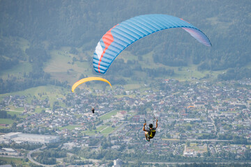 Three Paragliders Soaring Over the Cityscape