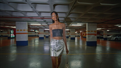 Stylish brunette model stepping night parking alone. Lady looking camera posing