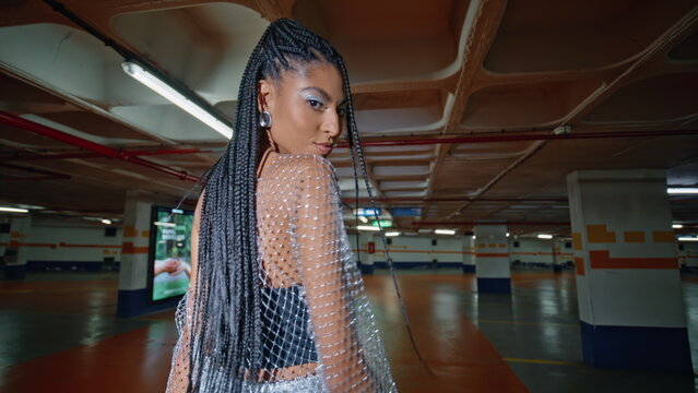 Modish woman posing underground parking back view. Brunette dancing shoulders