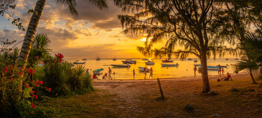 View of boats and people on Mon Choisy Public Beach at sunset, Mauritius