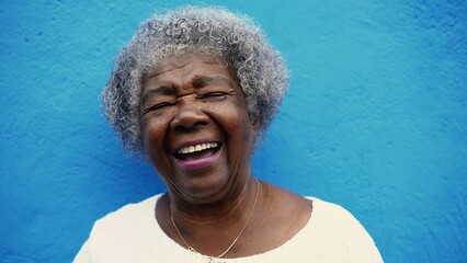 One happy senior African American elderly woman with gray hair laughing and smiling in blue wall...