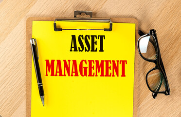 ASSET MANAGEMENT text on a yellow paper on wooden background