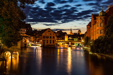 Fototapeta na wymiar Beleuchtete Gebäude bei Nacht an einem Fluss
