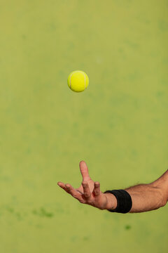 Man's hand tossing a tennis ball in a game