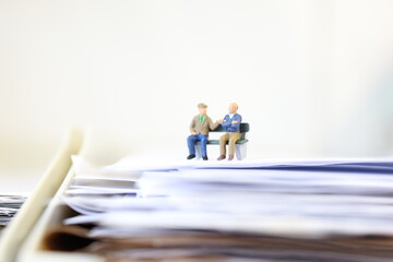 Pair of elder retired people sitting down on a bench in the office.