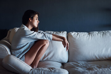 Depression, sad and woman relaxing on sofa in living room for loneliness at modern house. Mental...