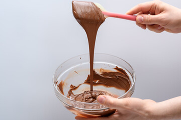 Proces temperowania czekolady, mieszanie rozpuszczonej czekolady silikonową szpatułką kuchenną - obrazy, fototapety, plakaty