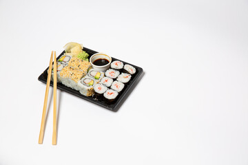 Sushi to go in a black takeaway box with wooden chopsticks on white background 