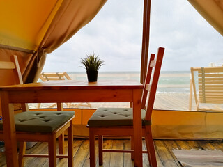 Sea view from a cozy room, a wooden table, two chairs and a flower.