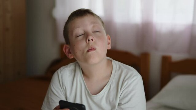 Portrait of child experiencing discomfort from swollen eye during allergic reaction at home. Suffering caucasian boy tries to look at camera, scratches swollen eye with hand due to unbearable itching.