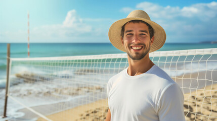 Closeup of the young man wearing a straw hat, standing on the sand beach next to the volleyball...
