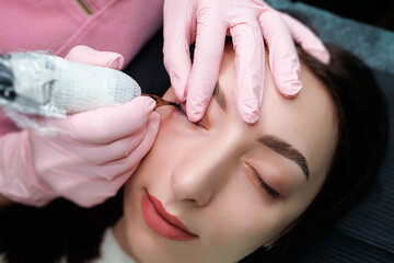 Obraz na płótnie Canvas Girl model at the procedure of permanent makeup of eyelashes. Permanent eye makeup and PMU eyelashes