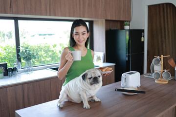 A woman is standing in front of a kitchen counter with a pug dog sitting on it