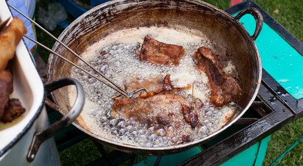 Photograph of pork frying in hot oil to prepare Peruvian chicharron. Peruvian food concept.