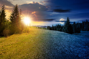 mountain landscape with sun and moon at spring equinox. meadow on the hillside with coniferous forest. day and night time change concept. mysterious countryside scenery in morning light - 753686412