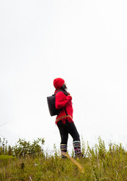 Explorando el invierno Chica con mochila y chompa rojo disfrutando del paisaje campestre bajo un cielo nublado,turista viajero,estilo de vida