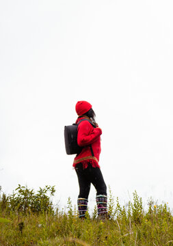 Explorando el invierno Chica con mochila y chompa rojo disfrutando del paisaje campestre bajo un cielo nublado,turista viajero,estilo de vida
