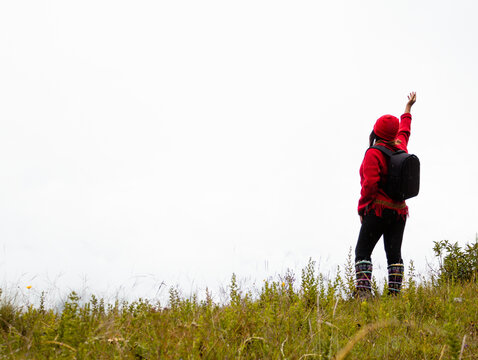 Explorando el invierno Chica con mochila y chompa rojo disfrutando del paisaje campestre bajo un cielo nublado,turista viajero,estilo de vida