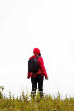 Explorando el invierno Chica con mochila y chompa rojo disfrutando del paisaje campestre bajo un cielo nublado,turista viajero,estilo de vida