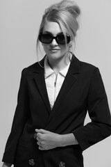 Beauty concept. Beautiful young blonde woman wearing black suit and sunglasses studio portrait....