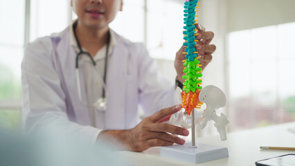 Young asian male doctor orthopedic explaining a back injury or disease to patient. Male doctor...