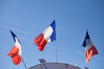 Trois drapeaux tricolores français devant un ciel bleu