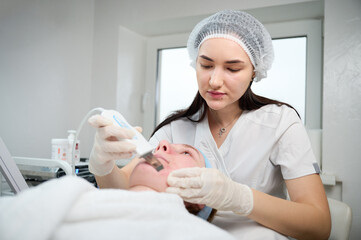 Close up of ultrasound skin cleaning and facial peeling procedure in beauty clinic. Macro shot of...