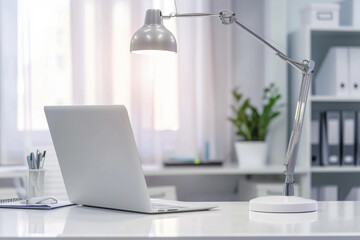 White desk with laptop, table lamp, stationery and decor over blurred background modern office .