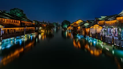 Gordijnen Attractive night scenery of traditional Chinese houses on both banks of a canal in a chilly and rainy evening at the ancient township of Wuzhen near Shanghai, China. © Joseph