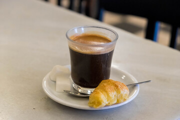 Vaso de café y mini croissant en un bar de Burgos