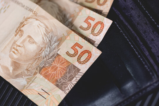 Notas do Real Brasileiro de 50 reais em uma carteira preta. Economia brasileira, salário e inflação.
