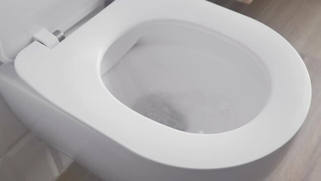 A full flush in the toilet with a large flow of fresh water into the sewer. Wasteful use of outdated plumbing, plumbing and sewerage in the bathroom.