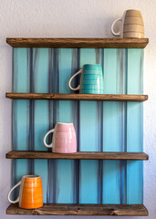 Tassen in einem Regal an der Wand diagonal angeordnet