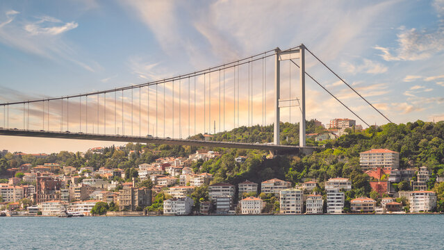 Bathed in the golden hues of sunset, the Bosphorus Bridge casts a mesmerizing reflection on the shimmering waters below, Istanbul, Turkey