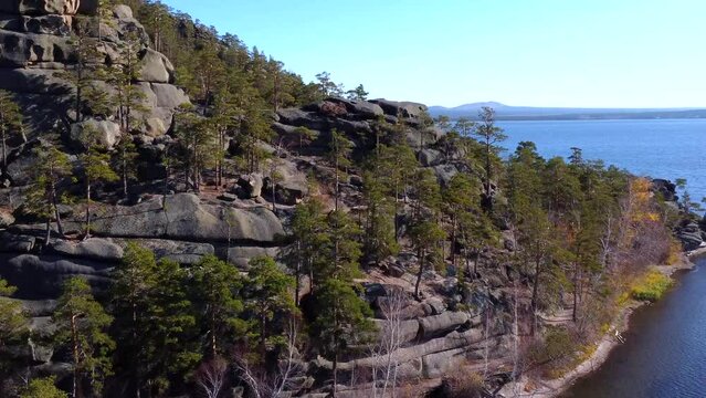 An aerial view of the mesmerizing nature of Borovoe, a huge stone rock and a stunning view of the turquoise Lake Burabay, surrounded by coniferous trees. Kazakhstan