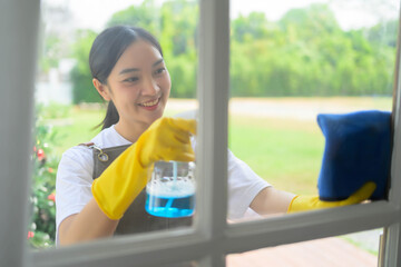 A woman is cleaning a window with a squeegee and a spray bottle