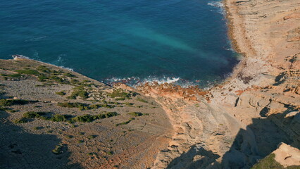 Drone turquoise sea water washing stone shore in super slow motion. Cozy bay