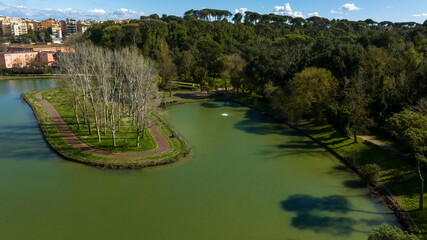 Aerial view of the small lake of Villa Ada, a public park in Rome, Italy. In the center of the lake there is a small island with trees and a green area.