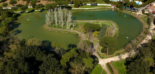 Fototapeta na wymiar Aerial view of the small lake of Villa Ada, a public park in Rome, Italy. In the center of the lake there is a small island with trees and a green area.