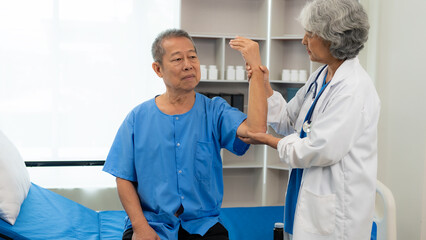 An elderly Asian man is doing physical therapy with the support of an elderly female nurse using dumbbells and tubes to exercise for a patient.