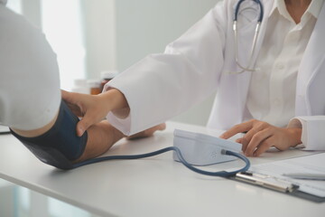 Male doctor uses a blood pressure monitor to check the body pressure and pulse of the patients who...