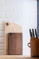 Wooden cutting boards leaned against the wall. In the foreground is a set of kitchen knives.