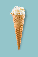 Popcorn in ice cream cone on blue background. - 753732480