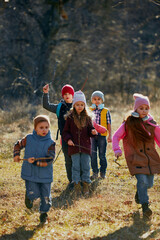Outdoor excursion with group of children, each expressing joy and fun in sunny day at forest. Concept of outdoor activities for children's development, school, childhood, fashion and style. Ad